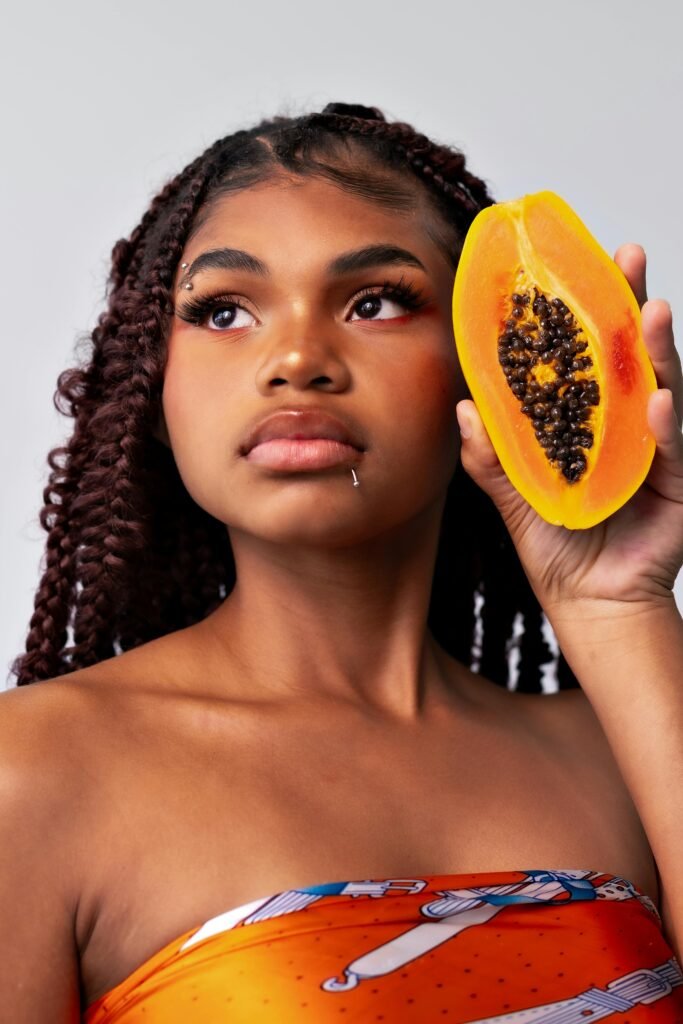 Portrait of an African woman with a papaya slice, showcasing natural beauty and tropical vibes.