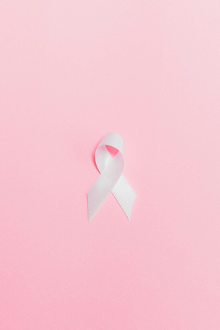 A pink ribbon symbolizing breast cancer awareness set against a light pink background.