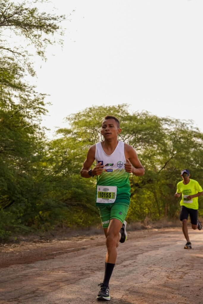 Two athletes running an outdoor marathon on a natural trail surrounded by greenery.