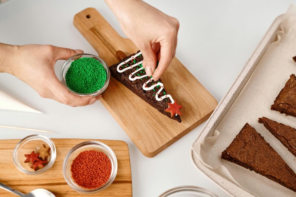 Person decorating Christmas brownies with colorful sprinkles and icing. Perfect for holiday baking themes.